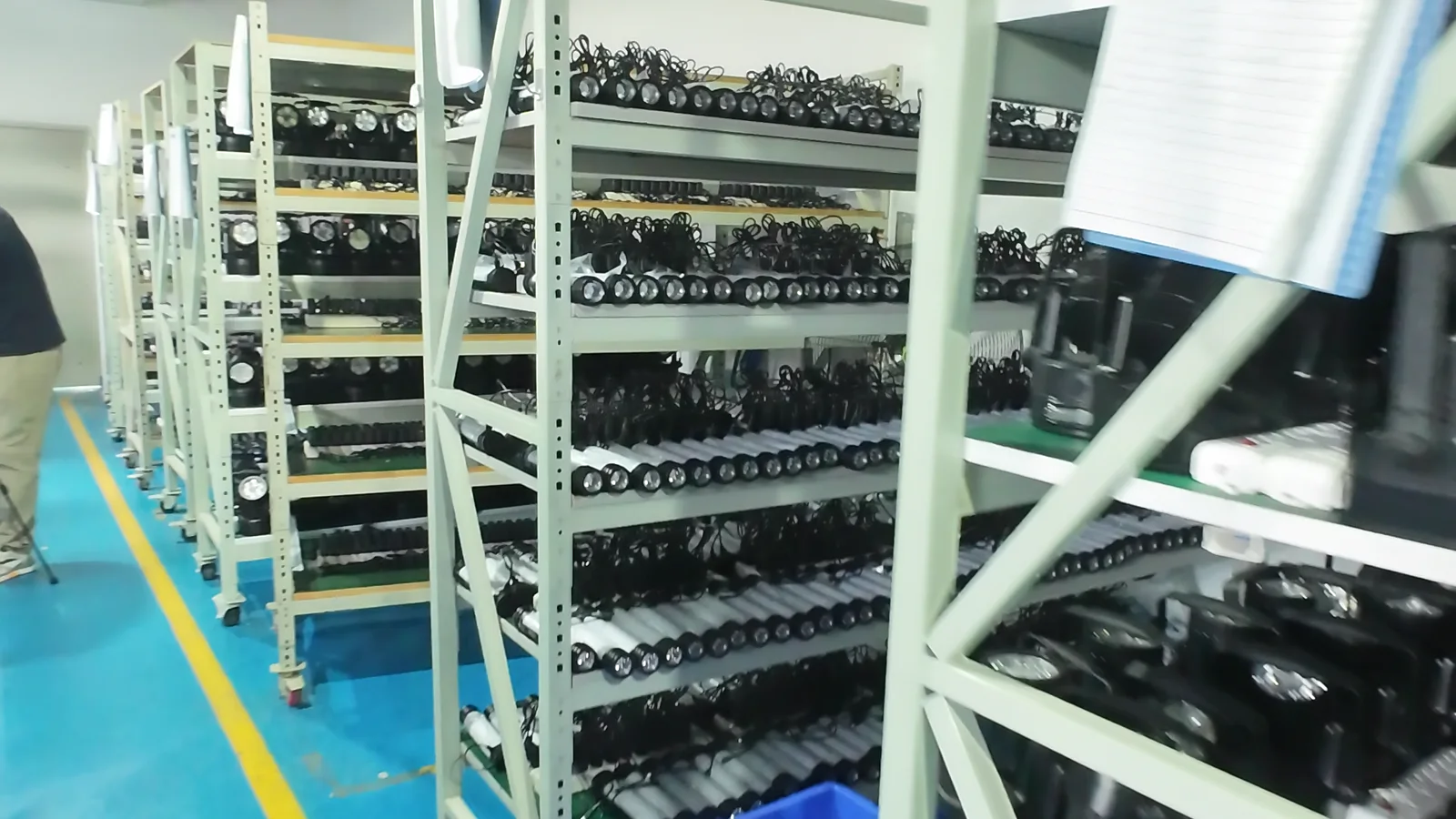 Rows of portable lights arranged on a rack with paper records during a production burn-in process