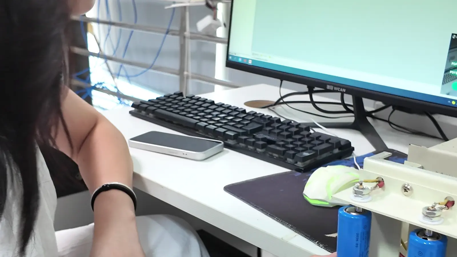Operator recording a portable-light battery test with cells connected to a monitoring setup